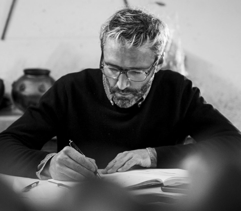 A candid portrait of Noé Duchaufour-Lawrance writing in his notebook