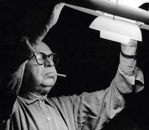 A portrait of Poul Henningsen inspecting his PH5 pendant lamp